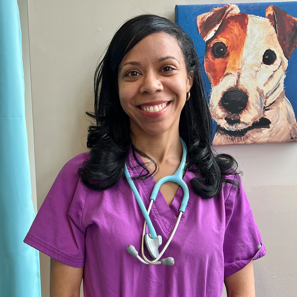 Smiling veterinarian in purple scrubs with a stethoscope.